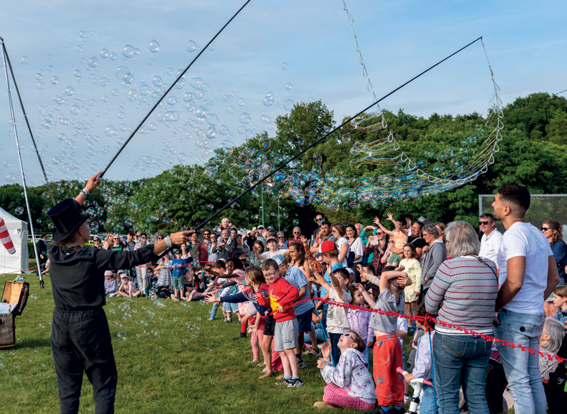 Un artiste fait apparaitre de nombreuses bulles devant une foule composée majoritairement d’enfants